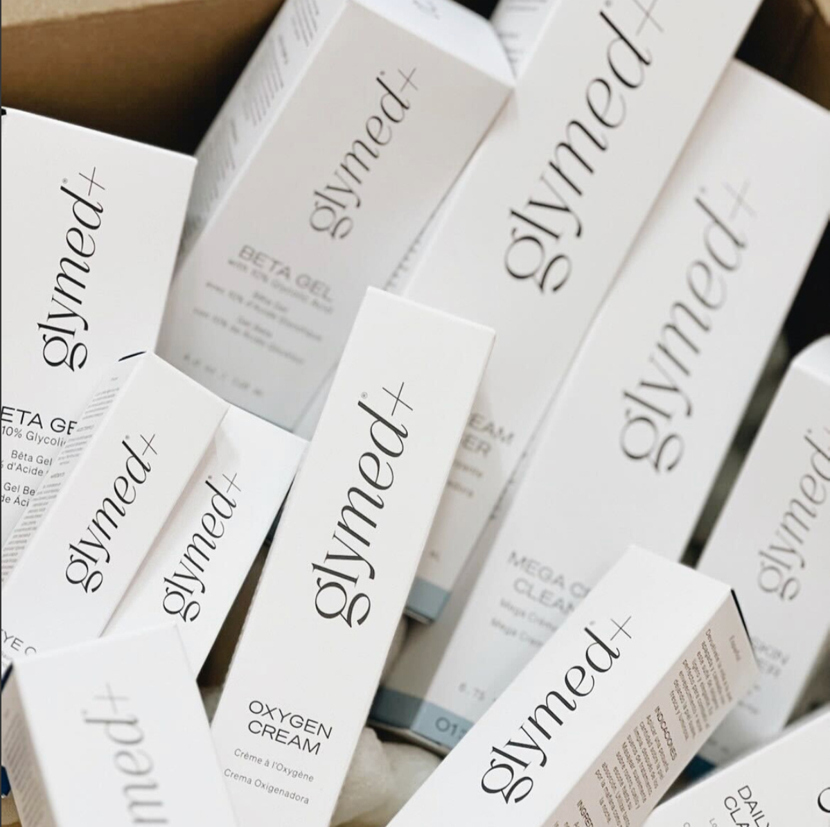 Assorted GlyMed Plus skincare products fresh out of the box, including cleansers, serums, and moisturizers